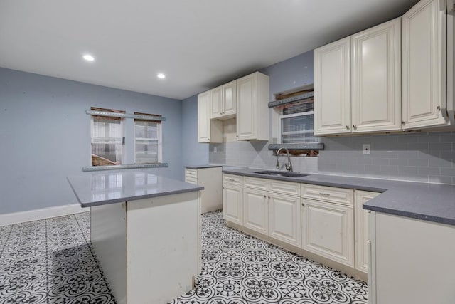 kitchen with backsplash, baseboards, recessed lighting, white cabinets, and a sink