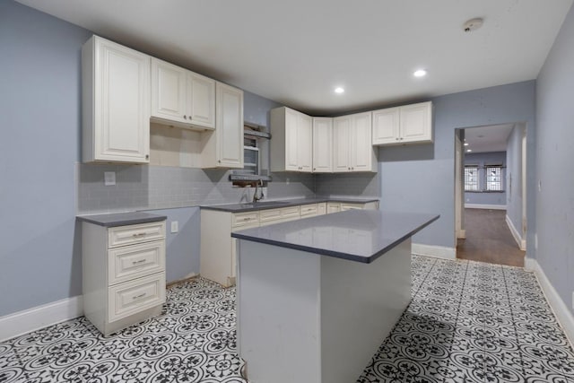 kitchen with white cabinets, baseboards, backsplash, and a center island