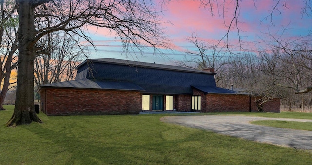 colonial inspired home with a front lawn, driveway, cooling unit, brick siding, and a chimney