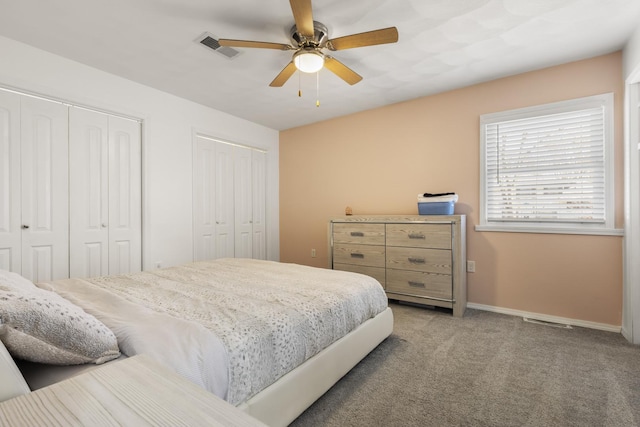 carpeted bedroom with visible vents, ceiling fan, baseboards, and multiple closets