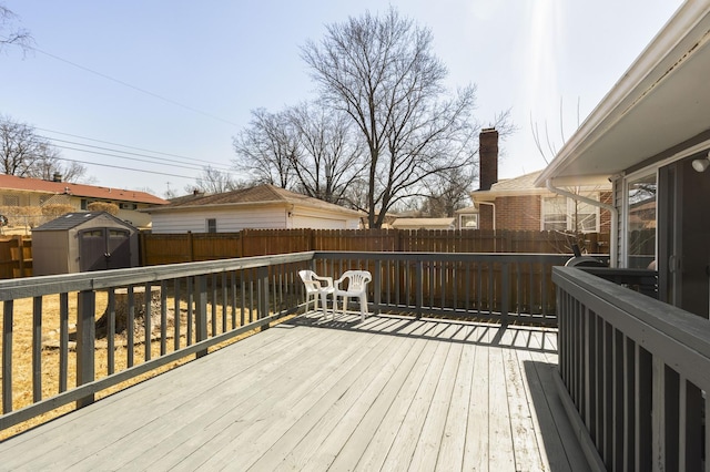 wooden deck featuring an outbuilding, a shed, and a fenced backyard