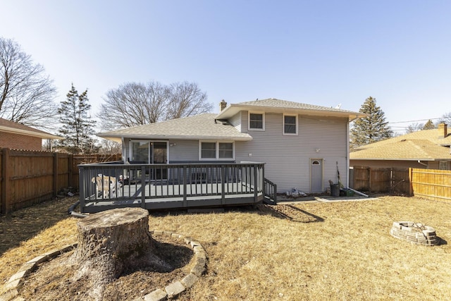 back of property with a fenced backyard, a chimney, and a wooden deck