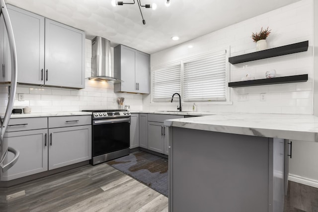 kitchen featuring electric range, dark wood-type flooring, gray cabinetry, a sink, and wall chimney exhaust hood