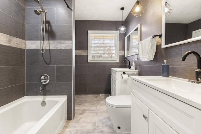 bathroom featuring vanity, tile walls, toilet, and shower / tub combination