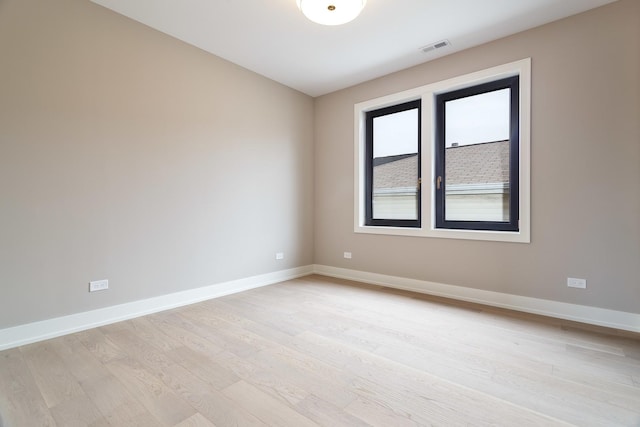 spare room featuring visible vents, light wood-type flooring, and baseboards