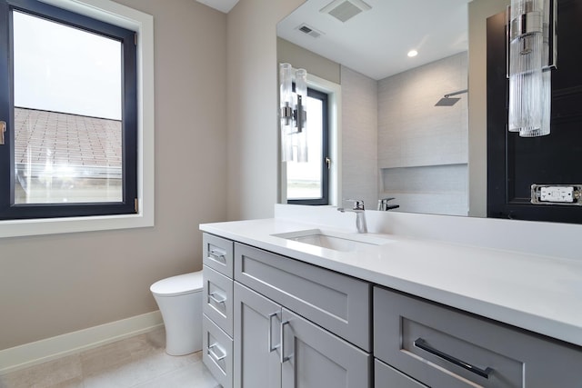 bathroom with vanity, baseboards, toilet, visible vents, and a tile shower