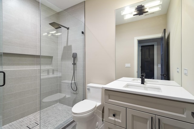 bathroom with a tile shower, vanity, visible vents, and toilet