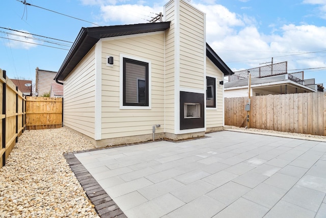 rear view of house featuring a patio area, a fenced backyard, and a chimney