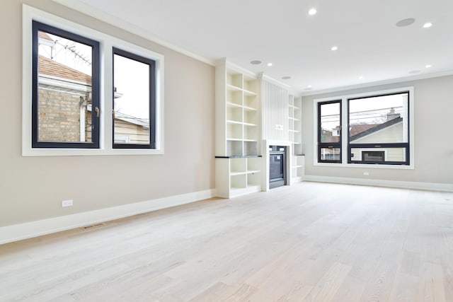 unfurnished living room featuring baseboards, built in shelves, light wood-type flooring, and ornamental molding
