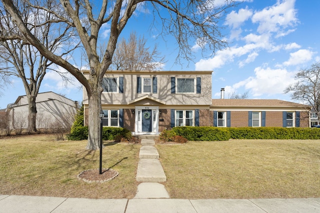 colonial-style house featuring brick siding and a front yard