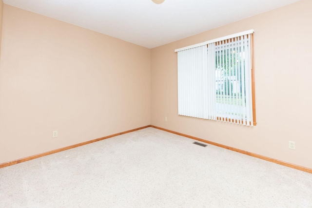 spare room with carpet flooring, baseboards, and visible vents