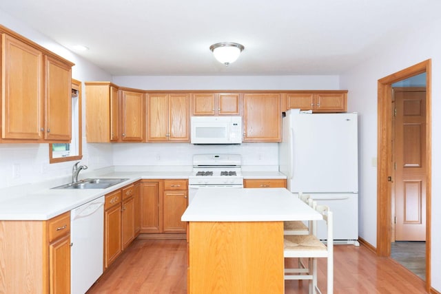 kitchen featuring light wood finished floors, a center island, light countertops, white appliances, and a sink