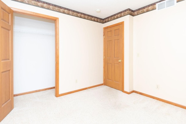 unfurnished bedroom with visible vents, baseboards, light colored carpet, and a closet