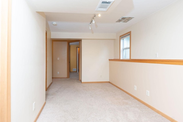 carpeted spare room with track lighting, baseboards, and visible vents