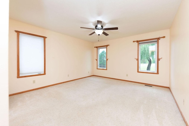 carpeted spare room featuring visible vents, baseboards, and a ceiling fan