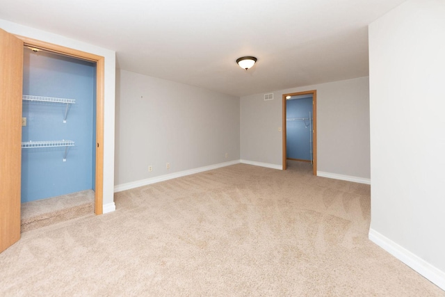 unfurnished bedroom featuring a spacious closet, visible vents, baseboards, carpet, and a closet