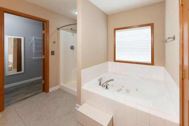 bathroom featuring tile patterned floors, a tub with jets, a stall shower, and baseboards