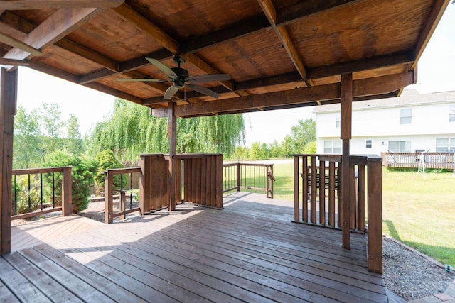 wooden deck with a lawn and a ceiling fan