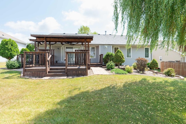 rear view of house featuring a lawn, a wooden deck, and fence