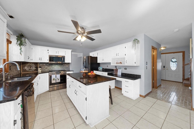 kitchen featuring light tile patterned floors, appliances with stainless steel finishes, a center island, and a sink