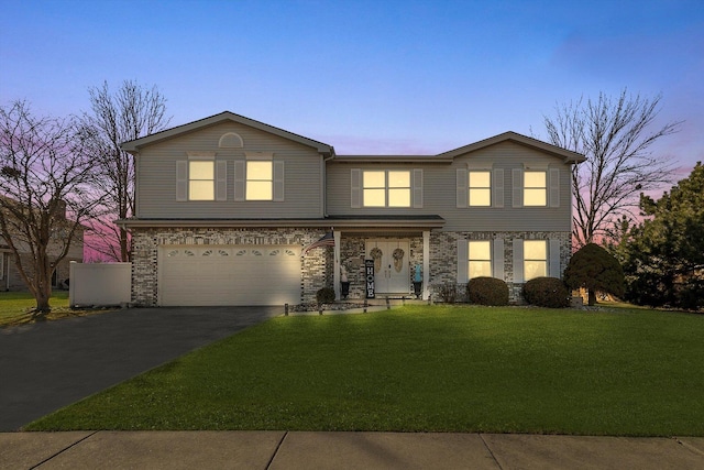 traditional-style house featuring aphalt driveway, a lawn, and a garage