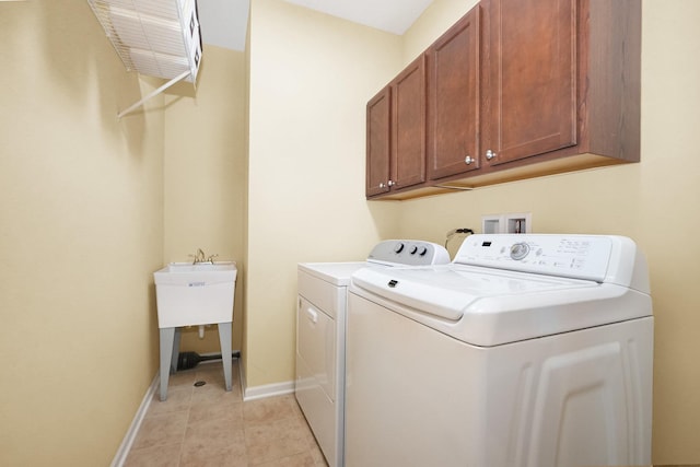 laundry area featuring baseboards, cabinet space, light tile patterned flooring, and washer and clothes dryer