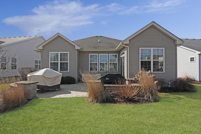 back of house with a yard, a shingled roof, and a patio