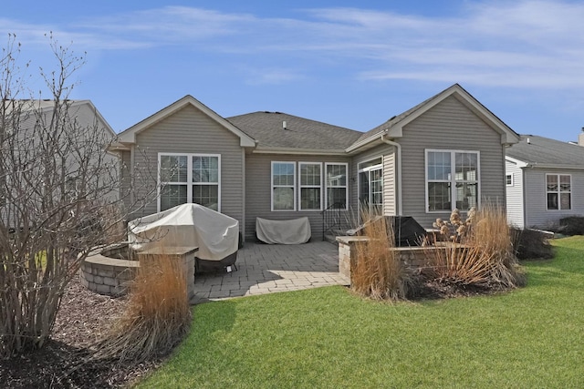 back of property with a patio, a lawn, and roof with shingles