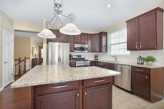 kitchen with backsplash, a center island, decorative light fixtures, stainless steel appliances, and a sink