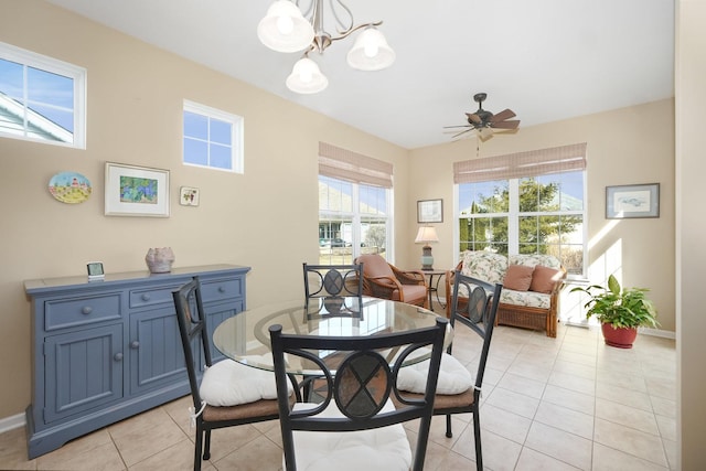 dining space with light tile patterned flooring, ceiling fan with notable chandelier, and baseboards