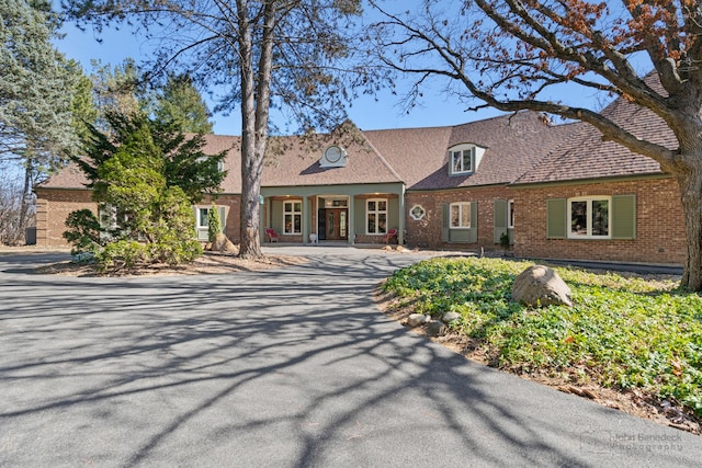 view of front of property with brick siding, roof with shingles, and driveway