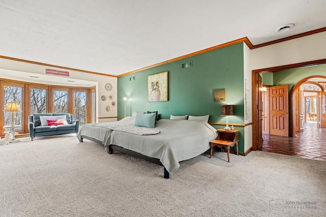 carpeted bedroom featuring arched walkways, visible vents, crown molding, and baseboards