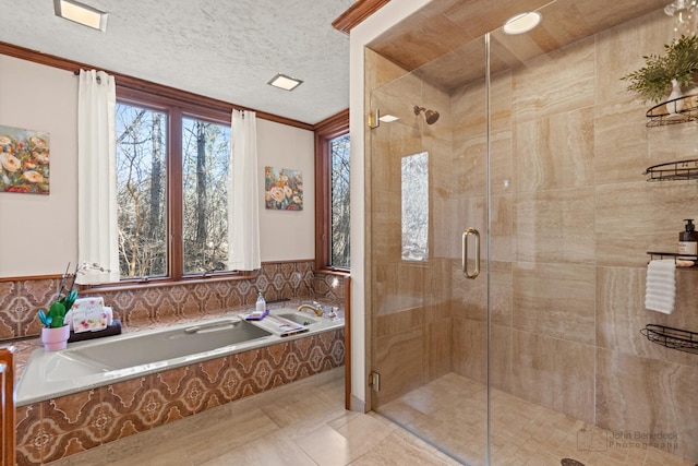 bathroom featuring a shower stall, a textured ceiling, a garden tub, and ornamental molding