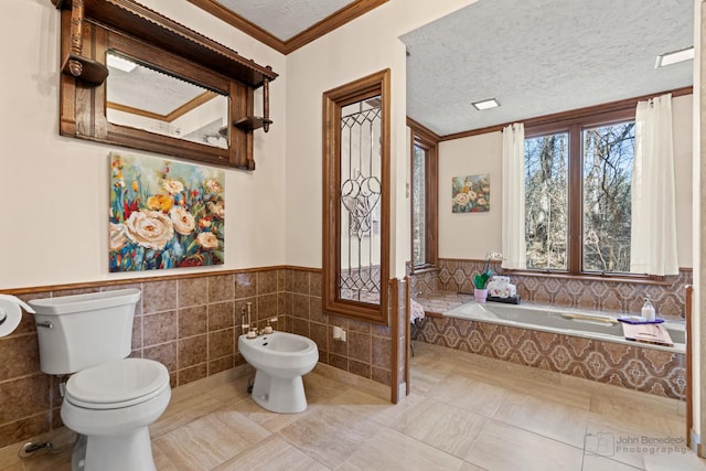 full bath featuring toilet, a textured ceiling, a bidet, crown molding, and a bath