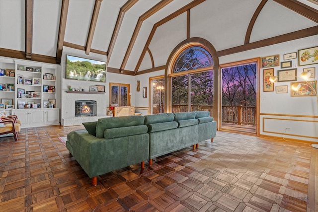 living area featuring beamed ceiling, high vaulted ceiling, a healthy amount of sunlight, and a fireplace