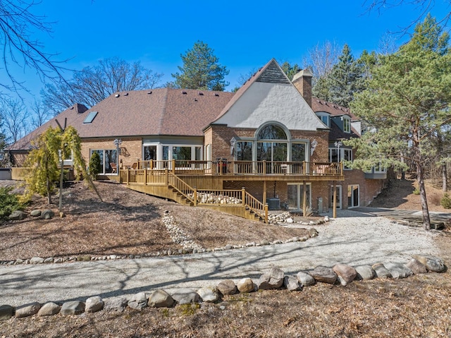 back of property with brick siding, stairway, a wooden deck, a chimney, and driveway