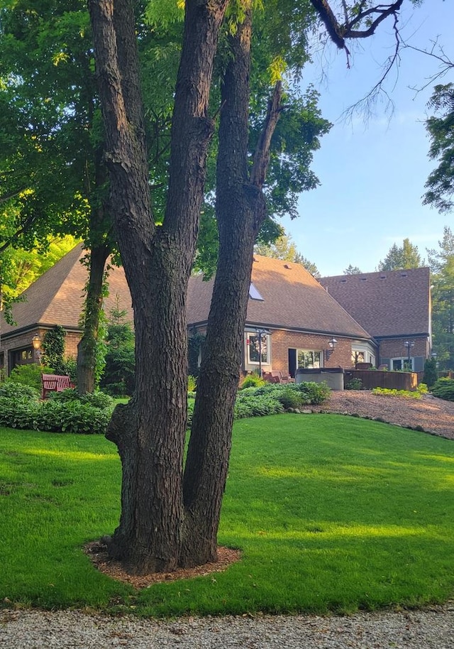 view of front of house with brick siding, a front lawn, and roof with shingles