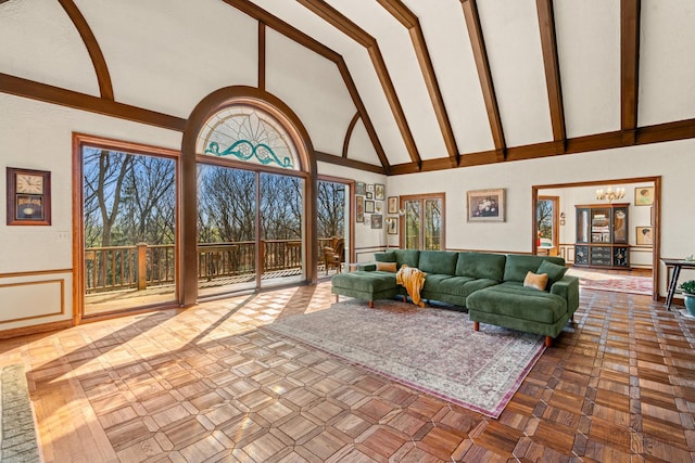 unfurnished living room featuring beam ceiling, high vaulted ceiling, and a chandelier