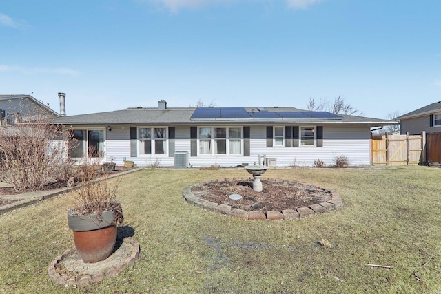 single story home with solar panels, a yard, fence, and cooling unit