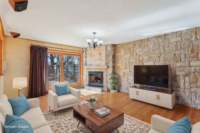 living area featuring wood finished floors, a chandelier, and a fireplace with raised hearth