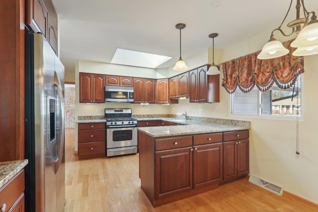 kitchen with visible vents, light wood-type flooring, a peninsula, a skylight, and stainless steel appliances