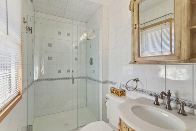 bathroom featuring a healthy amount of sunlight, a stall shower, tile walls, and toilet