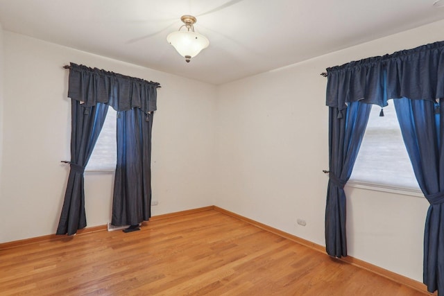 spare room with a healthy amount of sunlight, light wood-type flooring, and baseboards