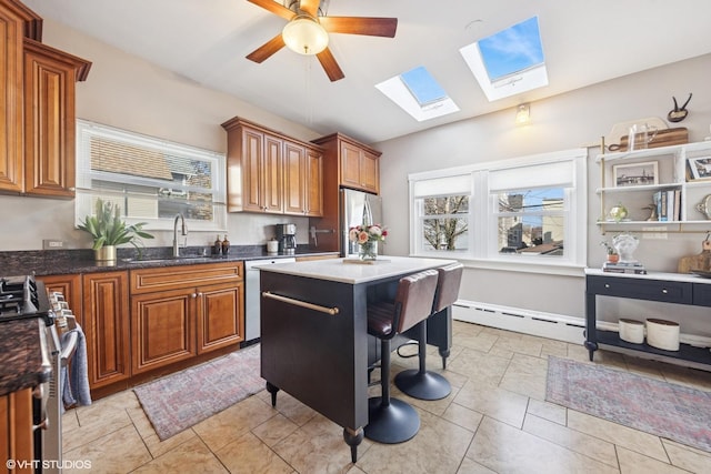 kitchen with brown cabinets, a sink, a baseboard heating unit, stainless steel appliances, and a healthy amount of sunlight