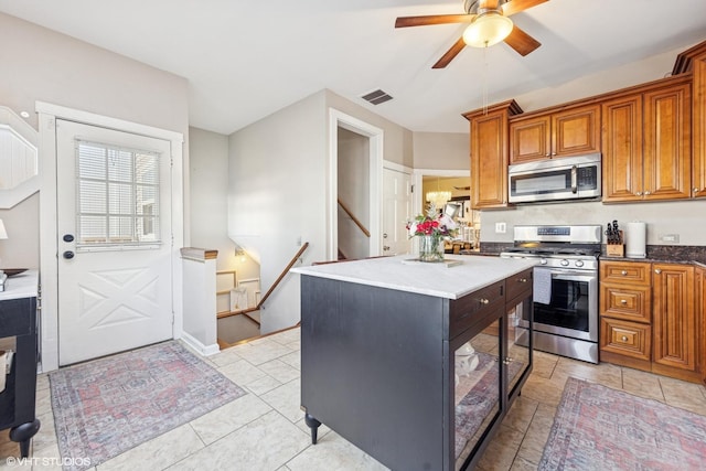 kitchen with visible vents, a ceiling fan, a kitchen island, appliances with stainless steel finishes, and brown cabinetry