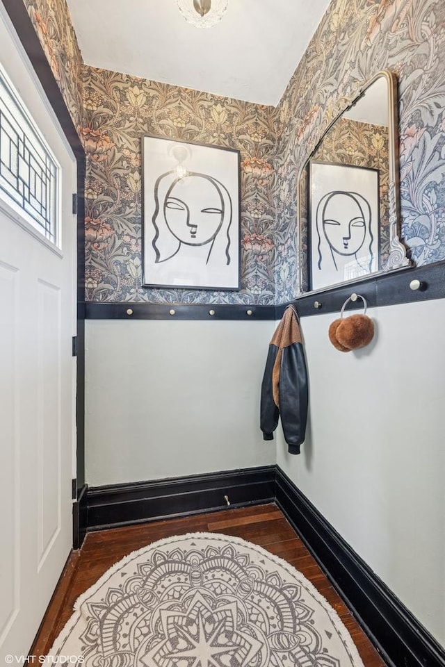 foyer entrance featuring wallpapered walls, baseboards, and wood finished floors