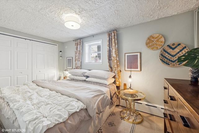 bedroom with a closet, baseboard heating, tile patterned flooring, and a textured ceiling