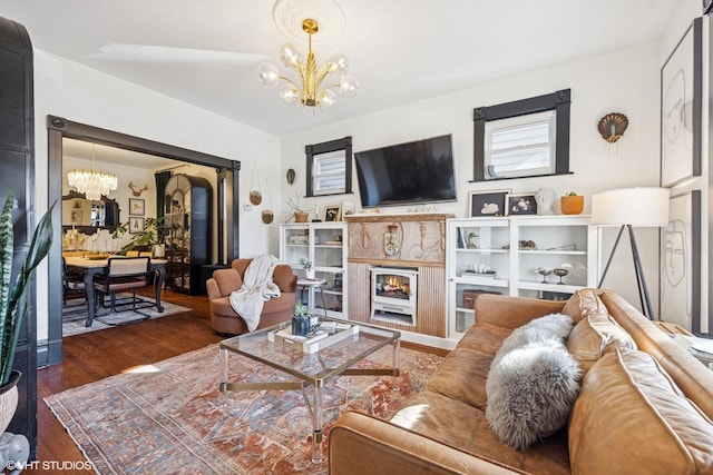 living room with a notable chandelier, a fireplace, and wood finished floors