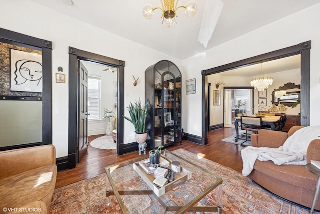 living room featuring an inviting chandelier, baseboards, and dark wood-style flooring