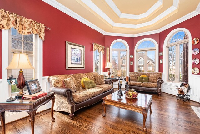 living room with a tray ceiling, wood finished floors, crown molding, and plenty of natural light
